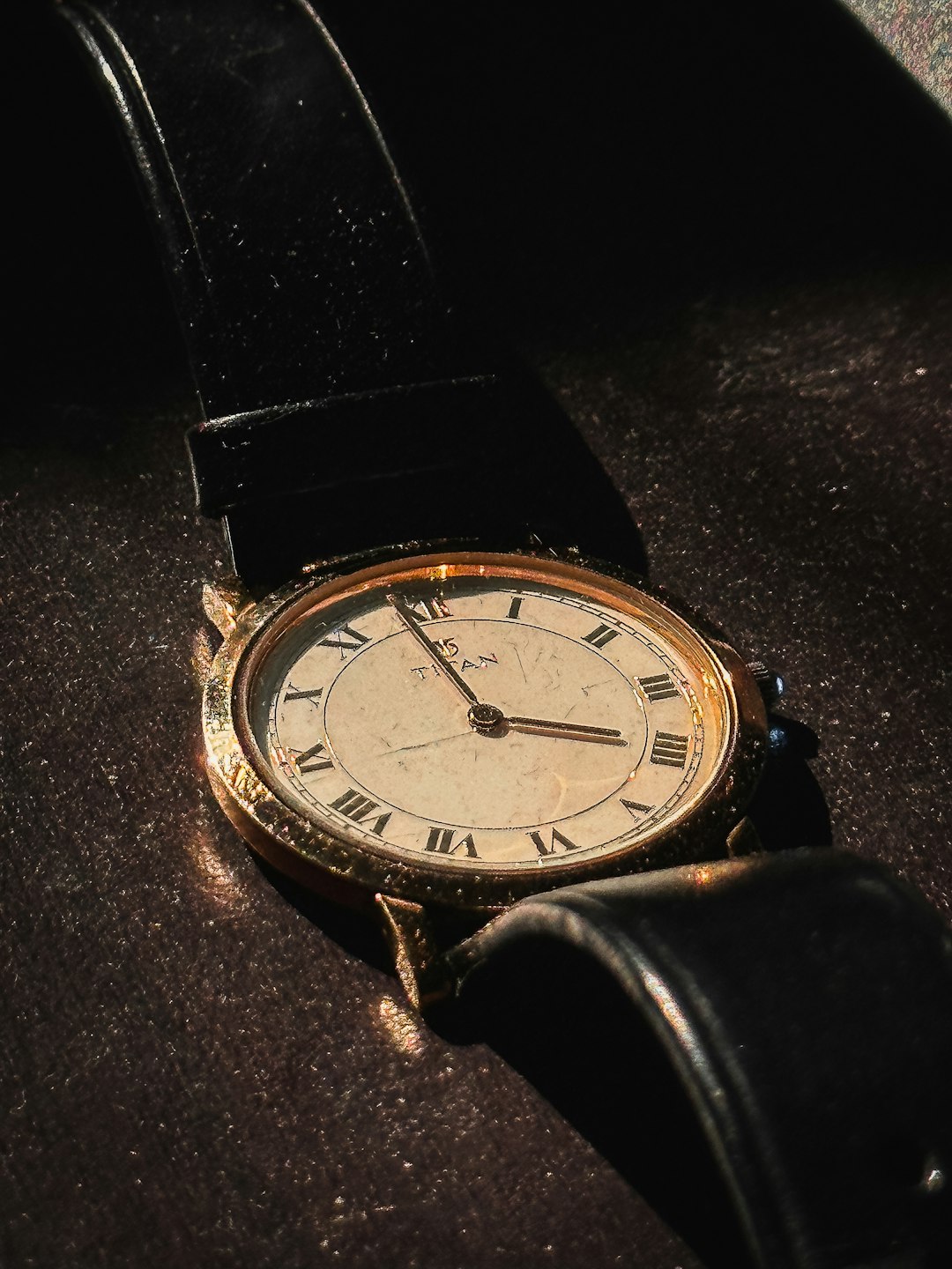 A gold watch with a black leather strap.